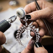 A jeweller polishing a marquise diamond spray at the bench